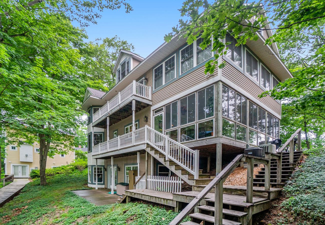 Front view of cottage, includes lower level back door, first floor balcony, second floor balcony and 2 staircase entry points